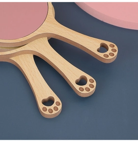 Close-up of wooden hand mirror handle featuring a cute hollowed-out cat paw design
