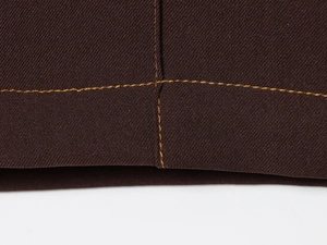 Detailed close-up of dark brown twill fabric with contrast yellow stitching detail