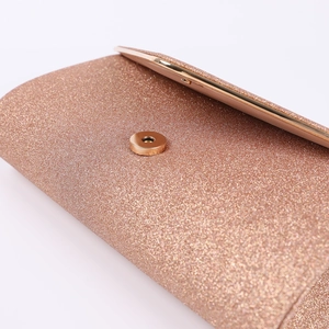 Detailed close-up of champagne gold glitter evening clutch with round magnetic clasp closure