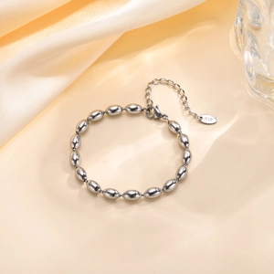 Close-up of polished silver oval bead chain bracelet with K18 engraving and lobster clasp