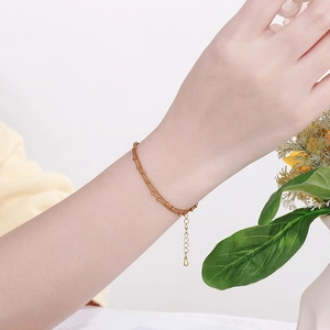 Gros plan d'un bracelet double couche en or à perles avec détail de pendentif goutte