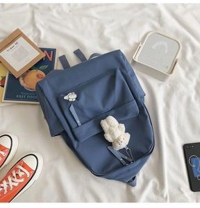Blue canvas school backpack with cute cartoon badges and bear pendant on white sheets