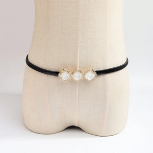 Detailed view of black elastic waist chain with square faux gemstones in gold frame