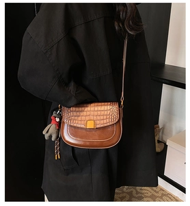 Détail du sac bandoulière marron motif crocodile avec breloque ours et boucle dorée