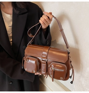 Detail of vintage brown shoulder bag showing front zipper pockets and matte texture