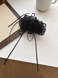Detailed close-up of a black mesh polka dot scrunchie with delicate ribbon accents