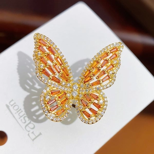 Macro shot of gold butterfly ring featuring orange baguette zircons and crystal pavé