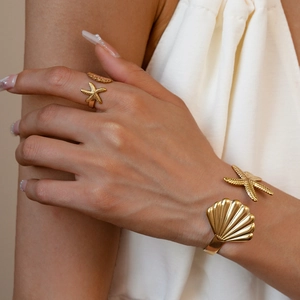 Detail of gold starfish ring and shell bangle on model for elegant vacation style
