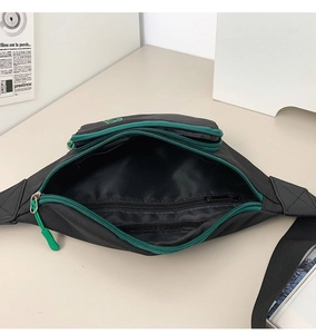 Detailansicht der schwarzen Brusttasche mit grünem Reißverschluss und Innenfach