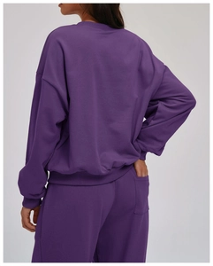 Detail of dark purple crewneck sweatshirt and joggers with ribbed cuffs and back pocket