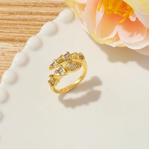 Macro detail of gold snake ring with baguette zircons on a white ceramic plate