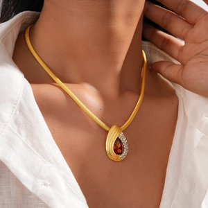 Detail of gold snake chain with red pear-shaped gemstone pendant and tiny diamonds