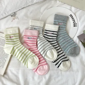 Detail of five colorful striped cotton socks with delicate embroidered lettering accents