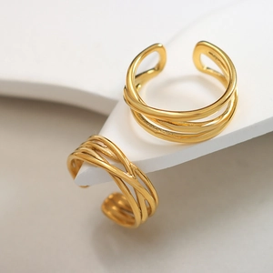 Elegant gold layered cross open rings with metallic luster on minimalist white stand