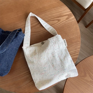 Detailed close-up of cream cotton canvas bag featuring colorful specks and magnetic clasp