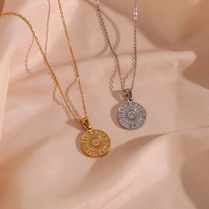 Detailed view of gold and silver sunburst compass pendants on champagne silk background