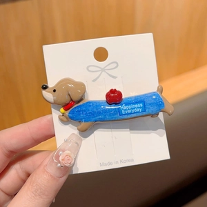 Detailed view of handmade brown dachshund hair clip with blue vest and apple motif