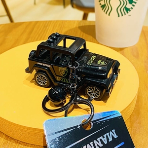 Detail of black police jeep keychain with bell and silver wheels on a yellow stand