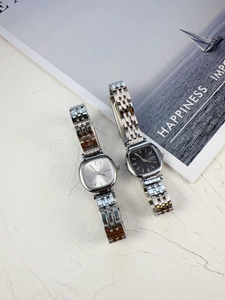 Detail showing two elegant square dial quartz watches with sleek metal mesh bands
