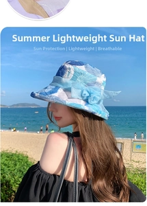 Detail of floral sun hat with blue mesh bow against a coastal beach background