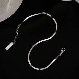 Minimalist silver stainless steel flat snake chain anklet with lobster clasp on black background