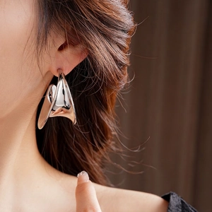 Modern wide C-shape silver earrings with exaggerated curved metal design on model