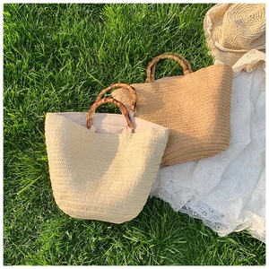 Close-up of woven straw tote bag texture and bamboo handle on lush summer grass