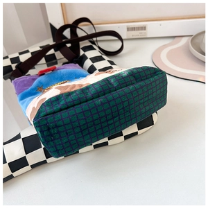 Detail of plush crossbody bag showing green plaid base and colorful velvet patchwork