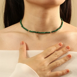 Close-up of green malachite stone necklace with golden beads on a model's neck