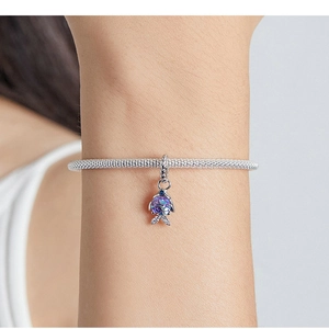 Macro view of a silver fish charm bracelet featuring purple and blue gradient scales