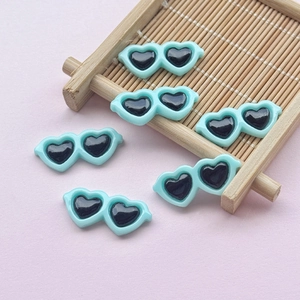 Close-up of mint green resin heart sunglasses charms for DIY craft and phone case decor