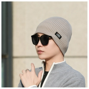 Detail of light khaki ribbed knit beanie showing soft wool texture and brand label