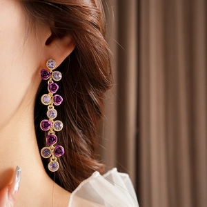 Gros plan de boucles d'oreilles roses pendantes avec cristaux violets sur un mannequin