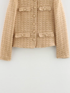 Detail of tweed texture with gold thread weaving and matching covered buttons on jacket