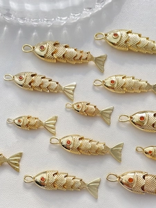 Makro-Detail von 14k vergoldeten, beweglichen Fisch-Anhängern für DIY-Schmuckherstellung