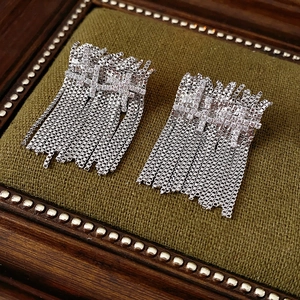 Détail de boucles d'oreilles à pompon argenté et zircon sur plateau velours
