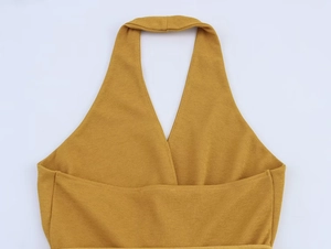 Dettaglio del top a dolcevita giallo senape con maglia testurizzata e scollo a V incrociato