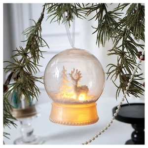 Close-up of a Christmas light-up ornament ball with a reindeer scene and warm LED light