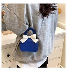 Mini royal blue PU leather handbag with white bow and silver bead chain shown on model