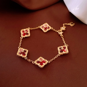 Macro view of 14K gold plated clover bracelet with red motifs and serrated edges