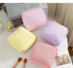 Vue à plat de trousses de maquillage à rayures seersucker en rose, violet, jaune et rouge