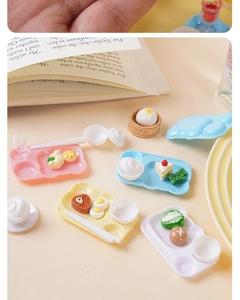 Close-up of miniature dollhouse meal sets with colorful trays and tiny resin food props