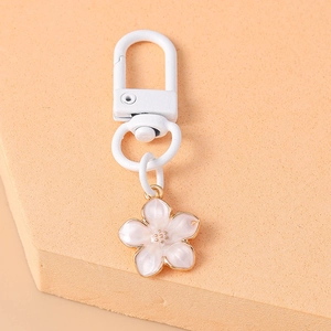 Close-up of a white cherry blossom keychain with gold-plated edges and metal clasp