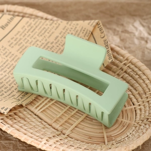 Detail of mint green matte rectangle hair claw clip on vintage newsprint in a basket