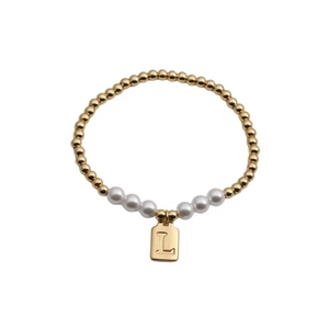 Detail of gold bead and white pearl elastic bracelet with letter L square pendant