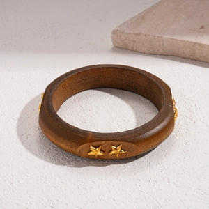 Detailed macro view of deep brown wooden bangle with inlaid golden star ornaments