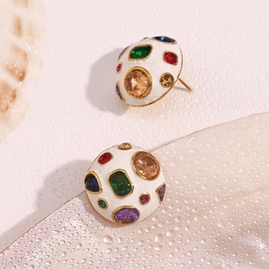 Close-up of gold plated round studs with white enamel and multi-color zircon stones