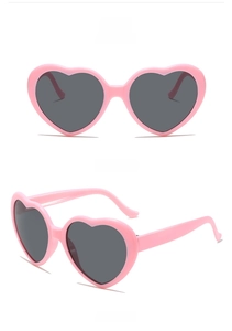 Macro view of light pink heart-shaped sunglasses with dark grey lenses and smooth frames