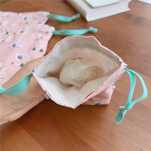 Detail of the pink cotton drawstring bag featuring small duck prints and blue cords