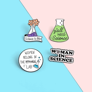 Detail view of science-themed enamel pins featuring lab flasks and inspirational text